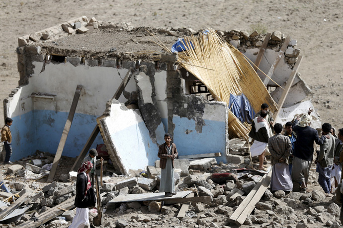 People gather on wreckage of house destroyed by air strike in Bait Rejal village west of Yemen' class=