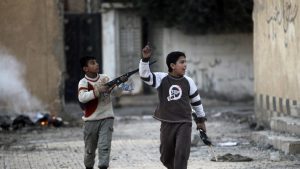 Children play with their toy weapons in a damaged school in Deir al-Zor, eastern Syria February 21, 2014. Picture taken February 21, 2014. REUTERS/Khalil Ashawi (SYRIA - Tags: POLITICS CIVIL UNREST CONFLICT) - RTX19ARC